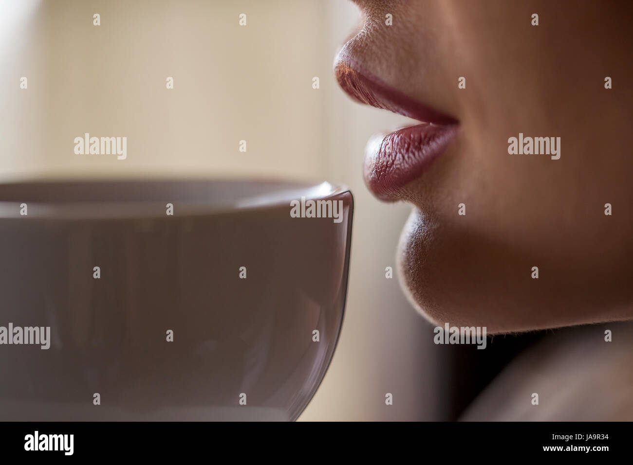 Schuss des Weibes Lippen berühren weiße Tasse Tee oder Kaffee hautnah. Stockfoto