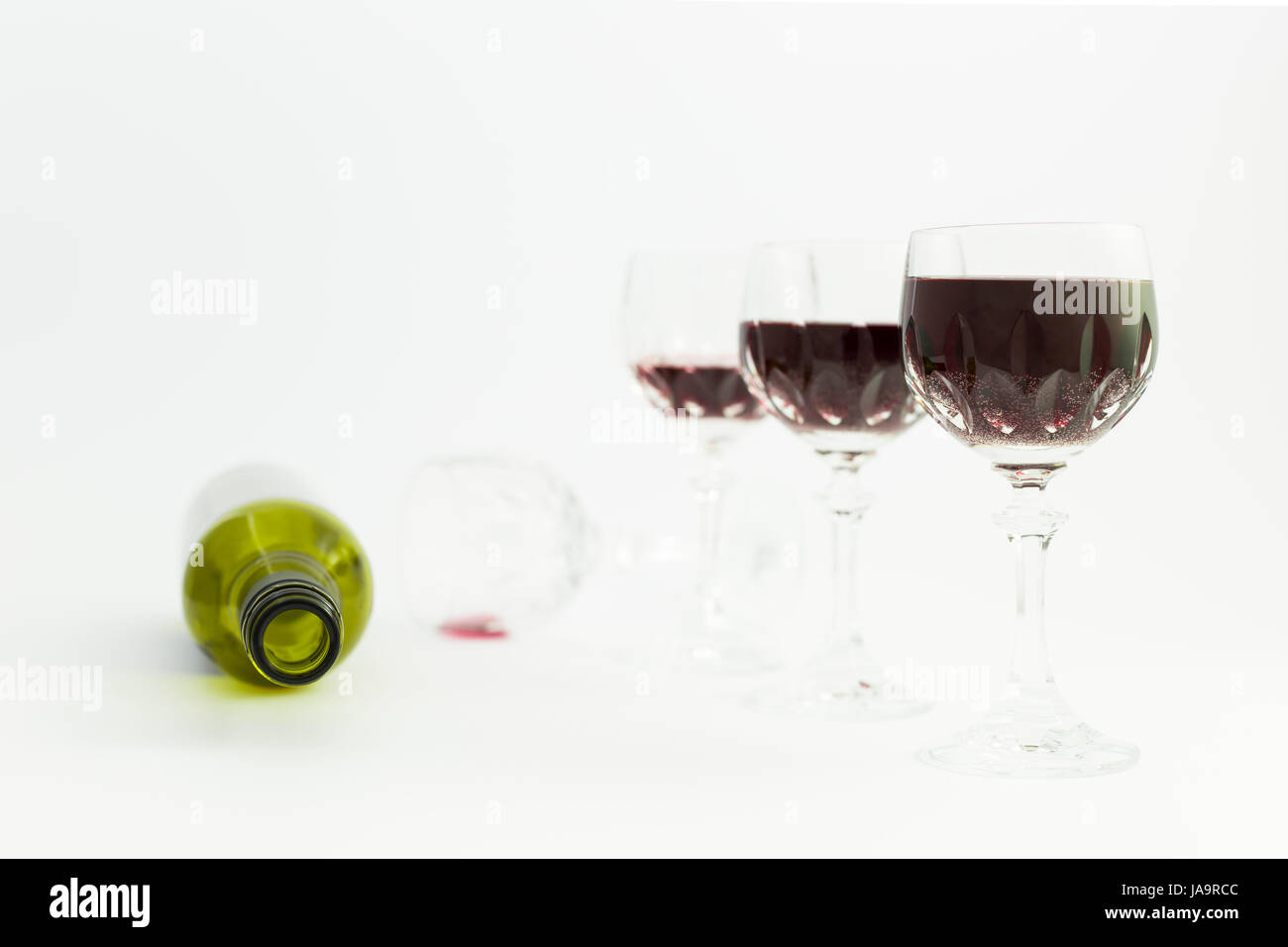 Konzept der Konsum von Alkohol, Alkoholismus und Missbrauch mit einer Reihe von schöne Kristallgläser mit Rotwein und eine leere Flasche gefüllt. Phasen der drin Stockfoto