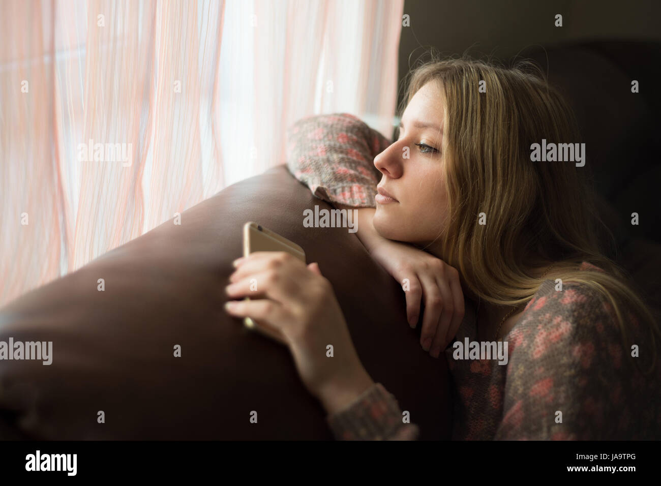 Teenager Mädchen vermisst das Fenster mit dem smartphone Stockfoto