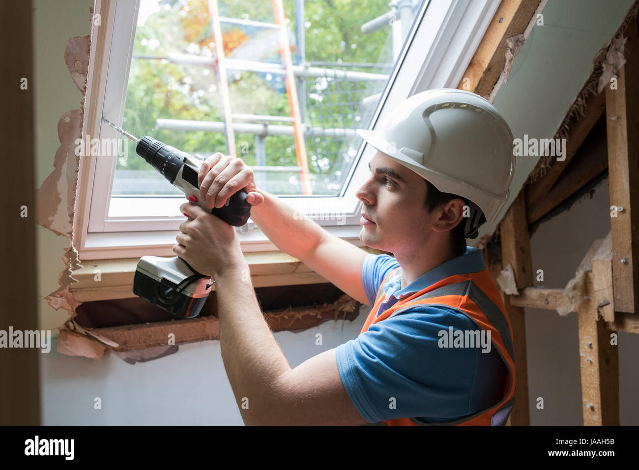 Bauarbeiter mit Bohrer, Ersatz Fenster zu installieren Stockfoto