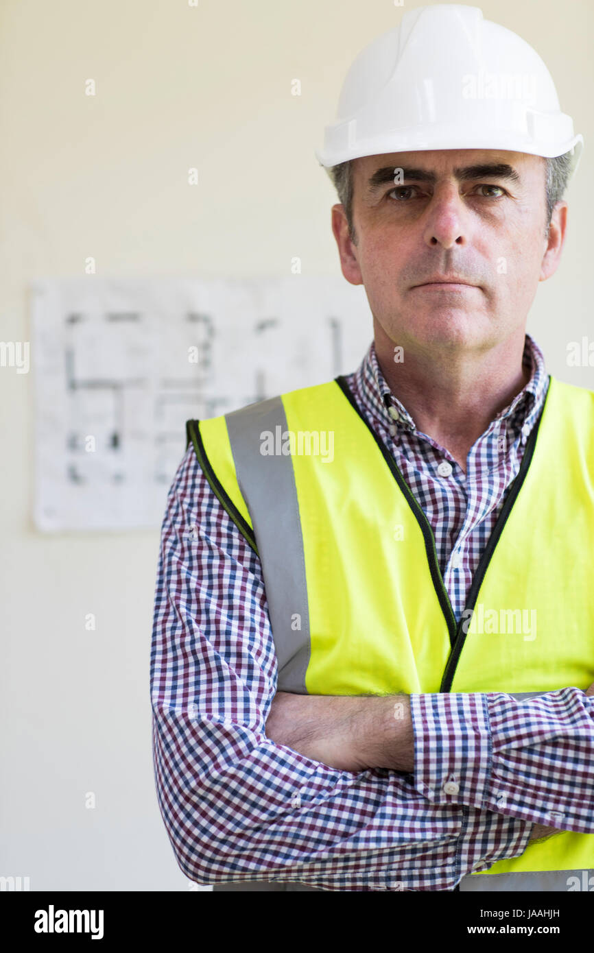 Portrait des Architekten tragen Schutzhelm mit Plänen im Hintergrund Stockfoto