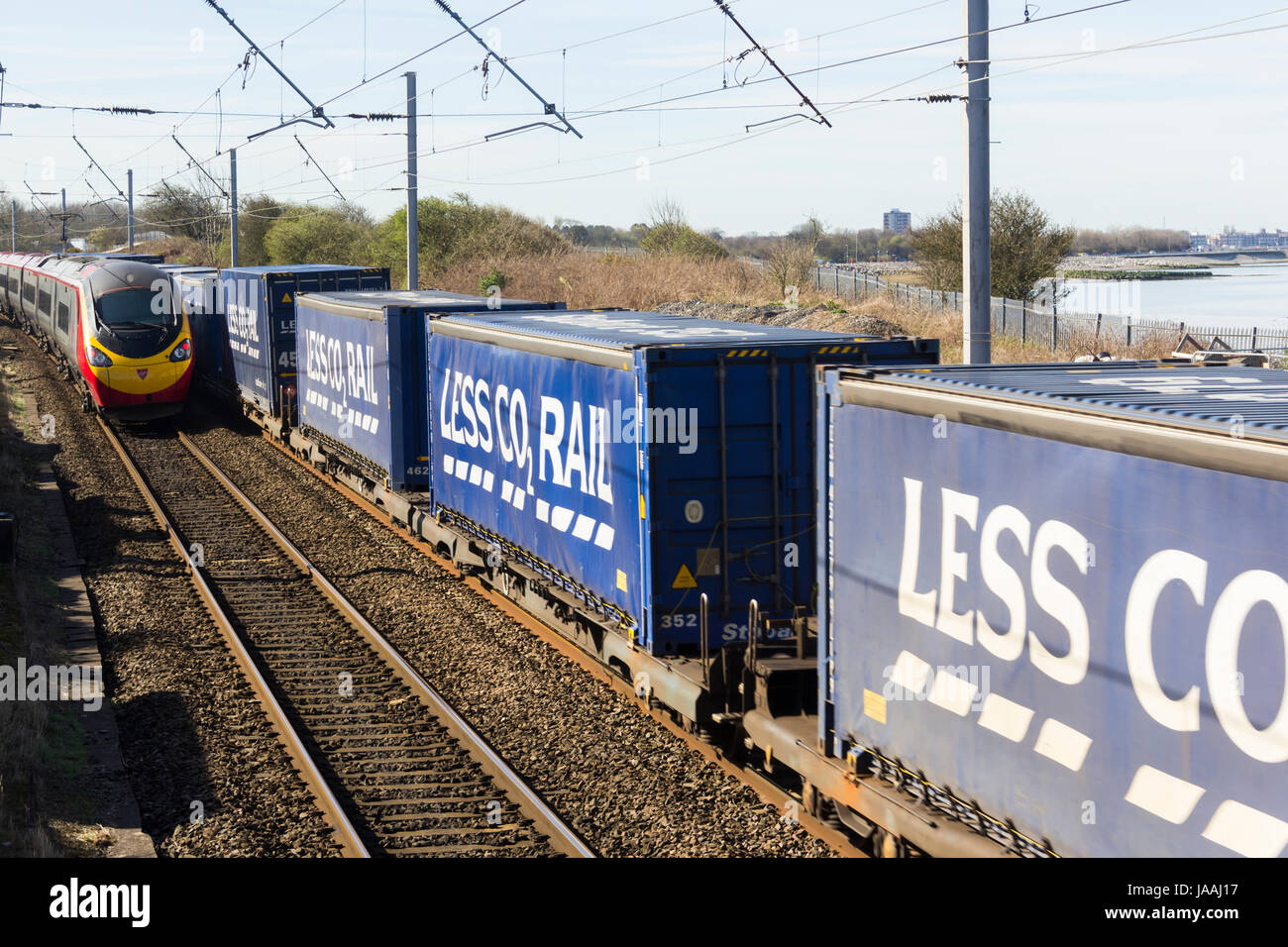 "Weniger CO2 Rail" (ein Tesco Marke) Container Zug passiert ein southbound Jungfrau pendolino auf der West Coast Main Line railway auf hest Bank, Lancashire. Stockfoto "Weniger CO2 Rail" (ein Tesco Marke) Container Zug passiert ein southbound Jungfrau pendolino auf der West Coast Main Line railway auf hest Bank, Lancashire. Stockfoto