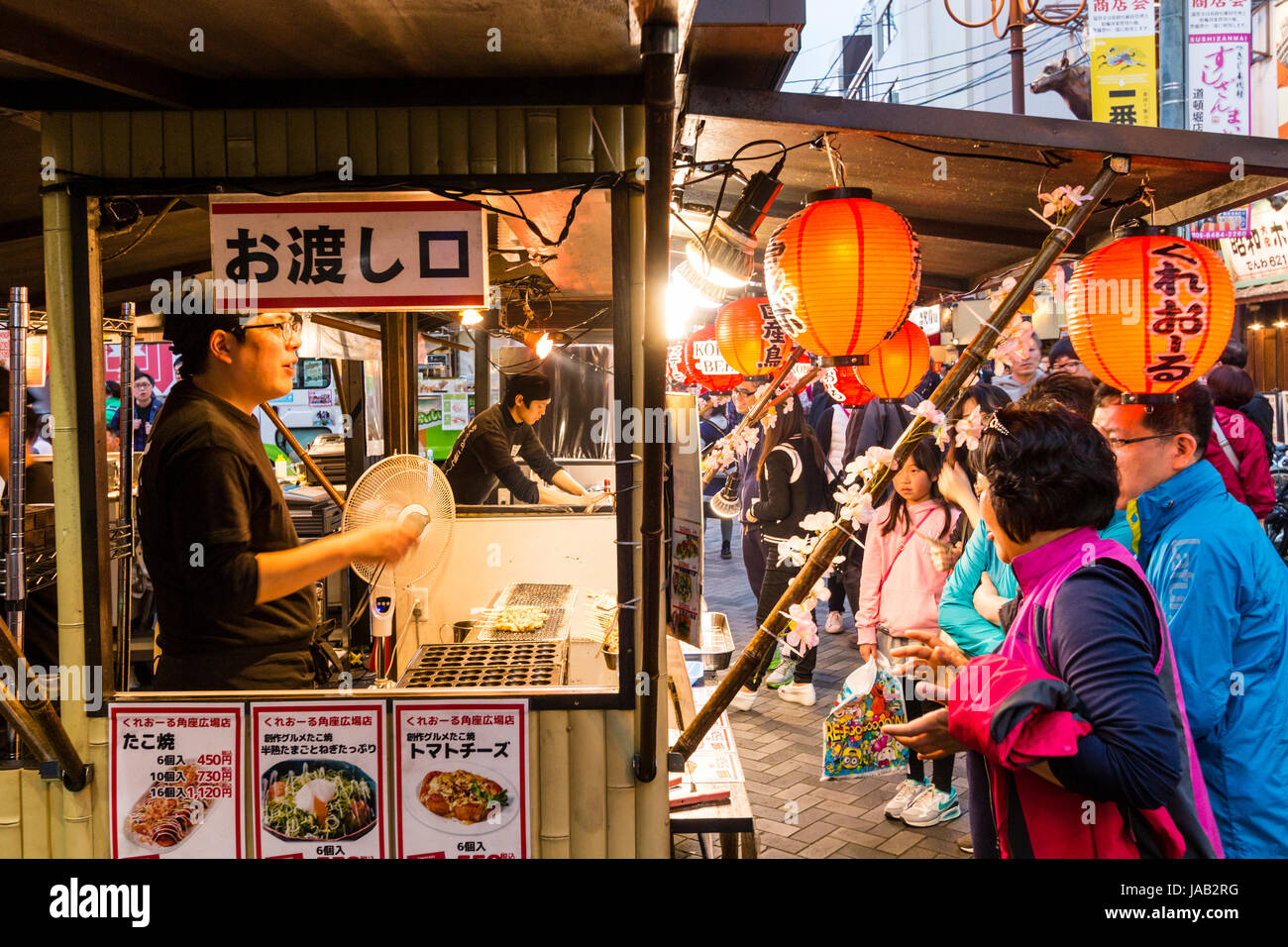 Japan, Osaka, Dotonbori. Nacht. Menschen bei Take away Zähler, Verkauf von Fried traditionelle japanische Küche. Chochin, Papier Laternen. Seitenansicht. Stockfoto