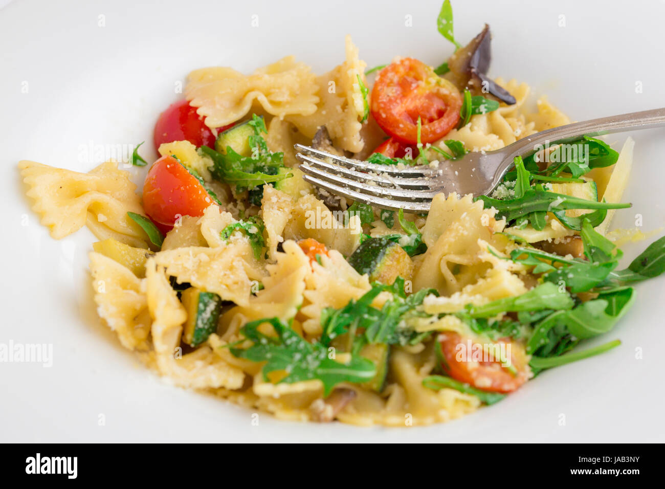 Ein typisch italienisches Nudelgericht serviert in einer weißen Schale. Dieses Rezept basiert auf Tomaten, Basilikum, Olivenöl und Rucula und Knoblauch. Stockfoto
