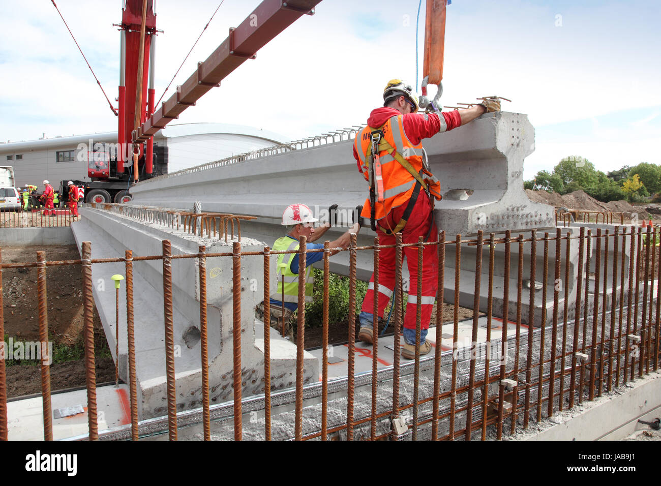 Arbeiter führen eine große, vorgegossenen Betonbalken in Platz für den Bau einer neuen Straßenbrücke in Woking, Surrey, UK Stockfoto