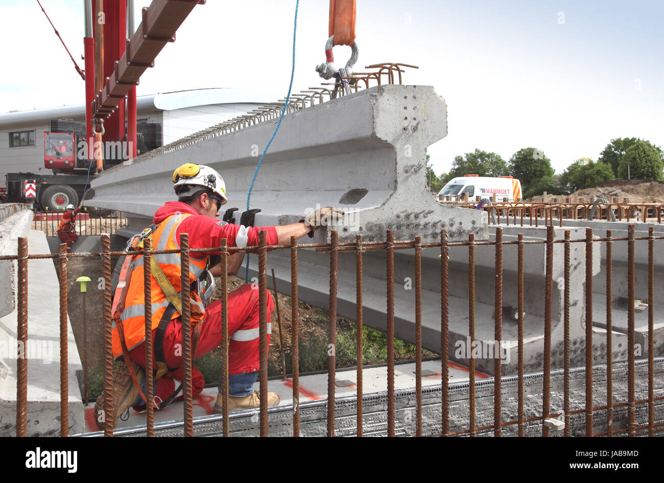 Arbeiter führen eine große, vorgegossenen Betonbalken in Platz für den Bau einer neuen Straßenbrücke in Woking, Surrey, UK Stockfoto