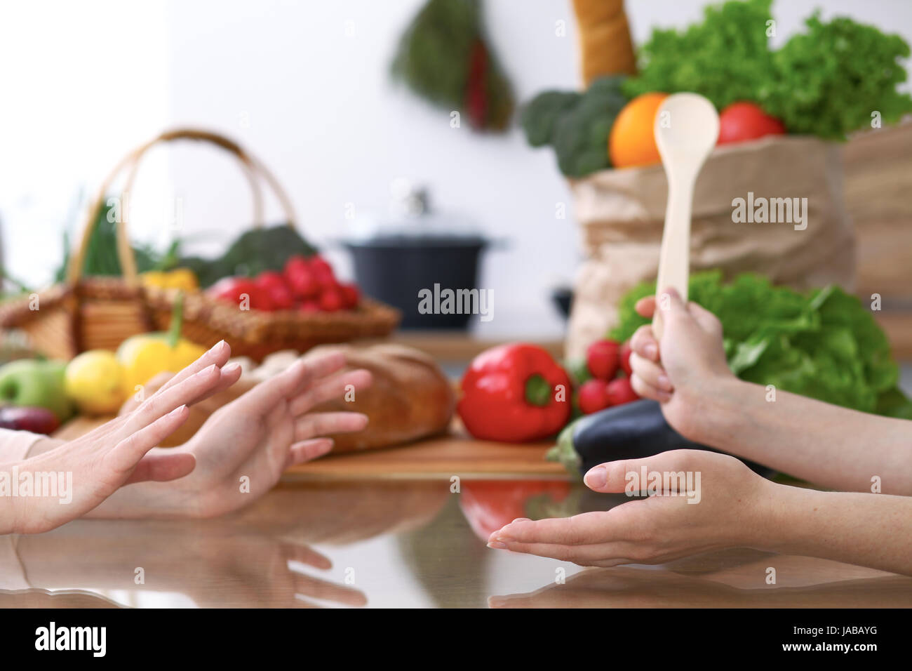 Zwei Frauen, die Diskussion über ein neues Menü in der Küche hautnah. Menschliche Hände von zwei Personen am Tisch unter frischem Gemüse gestikulierend. Kochen und Freundschaft Konzept. Stockfoto