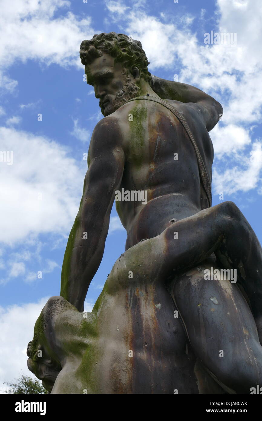 Skulptur aus Stein von zwei Männer kämpfen, dahinter ist ein Sommerhimmel. Stockfoto
