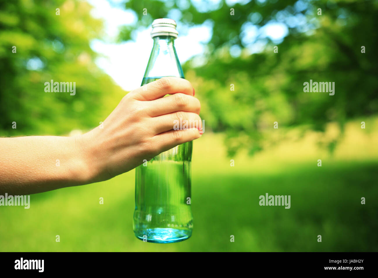 Gesunde Lebensweise Hintergrund. Flasche in der hand close-up Fitness Wasser. Mädchen mit Flasche Wasser am grünen Hintergrund. Stockfoto