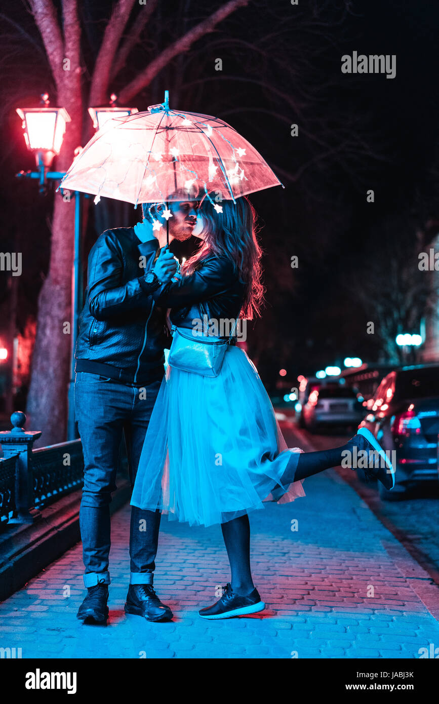 Mann und ein Mädchen küssen unter einem Regenschirm Stockfoto
