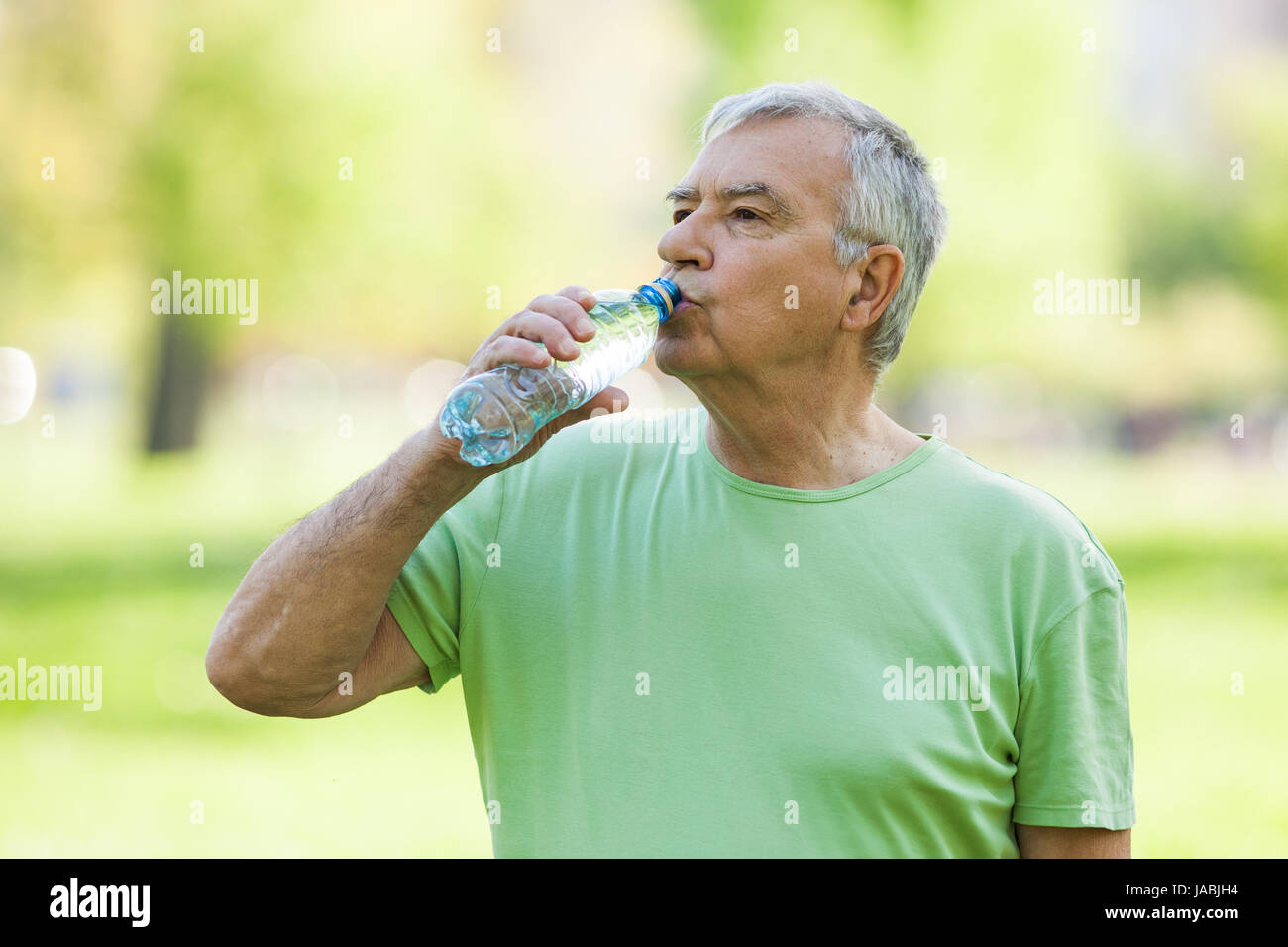 Senior Woman ist Trinkwasser nach dem Training im Park. Stockfoto
