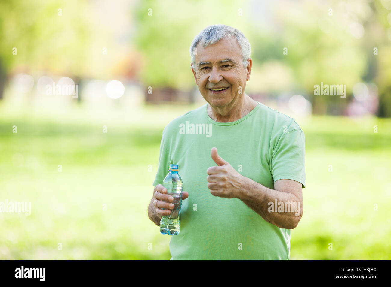 Senior Woman ist Trinkwasser nach dem Training im Park. Stockfoto