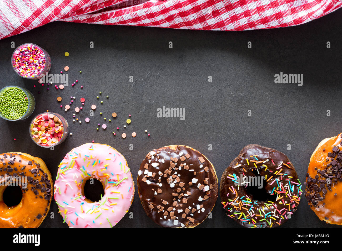 Donuts. Essen-Rahmen mit leckere glasierte Donuts und Küchentextilien. Ansicht von oben, Textfreiraum Stockfoto