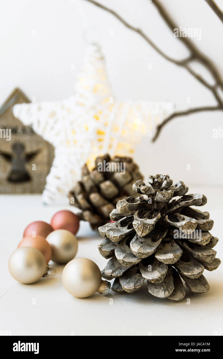White Christmas-Dekoration-Zusammensetzung, großer Tannenzapfen, verstreuten Kugeln, glänzenden Stern, hölzerne Kerzenständer, trockene Äste im Hintergrund, Nahaufnahme Stockfoto