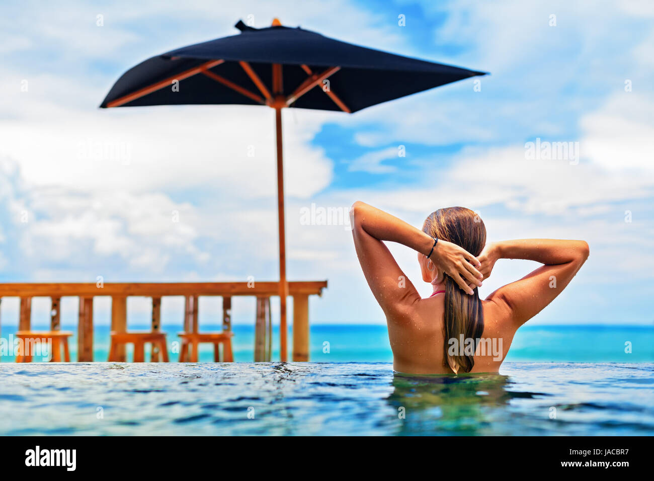 Junge glücklich Frau viel Spaß im Infinity-Außenpool mit Blick auf Meer Surfen. Positive Mädchen schwimmen, entspannen am Pool. Menschen am Familienstrand Urlaub. Stockfoto