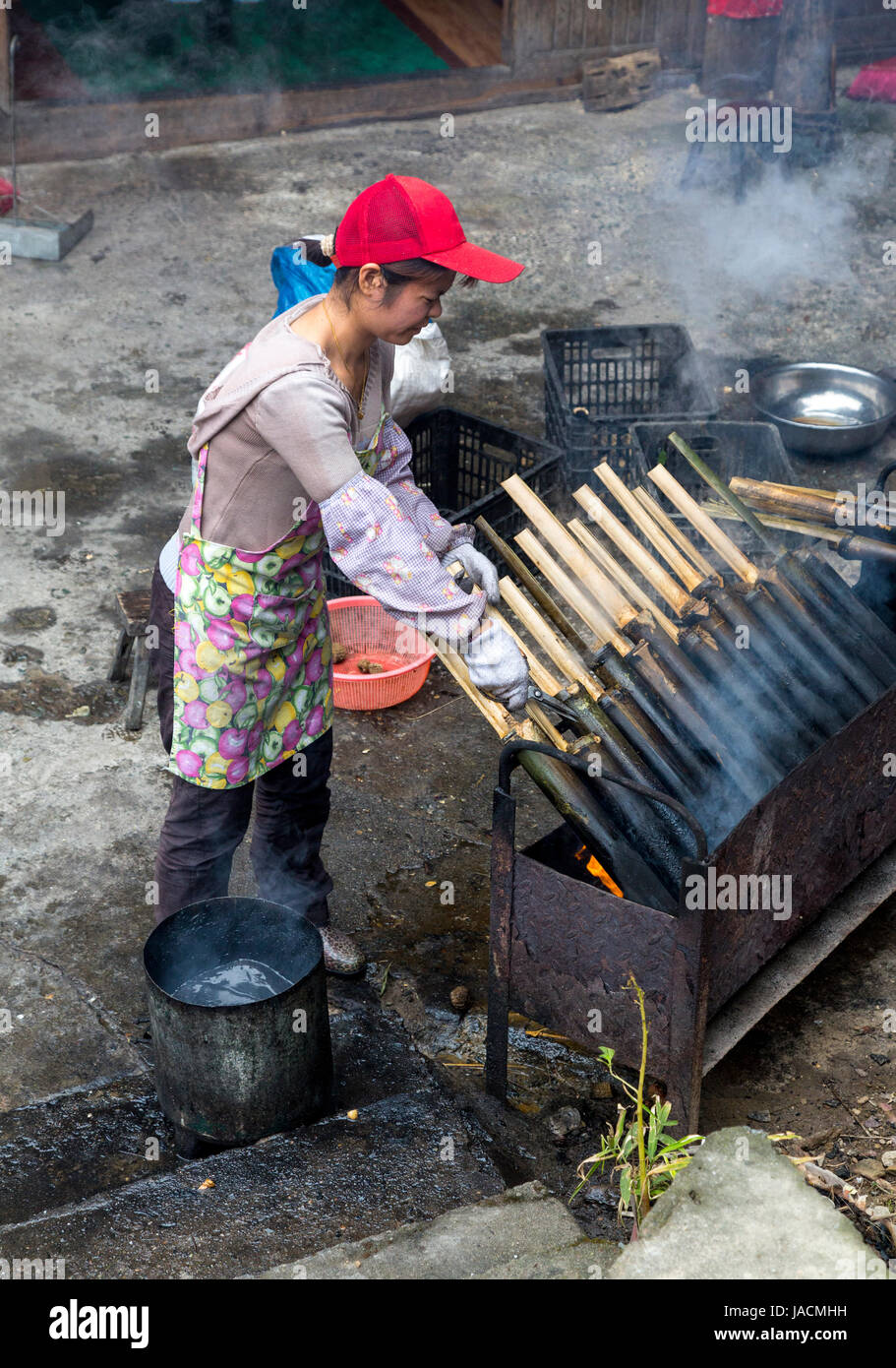 Longji, China. Frau Kochen Klebreis in Bambus Stockfotografie - Alamy