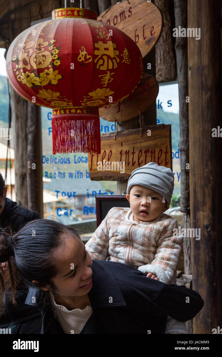 Longji, China.  Mutter und Kind auf Rücken am Eingang zum Boutique-Hotel bietet kostenlosen Internetzugang. Stockfoto