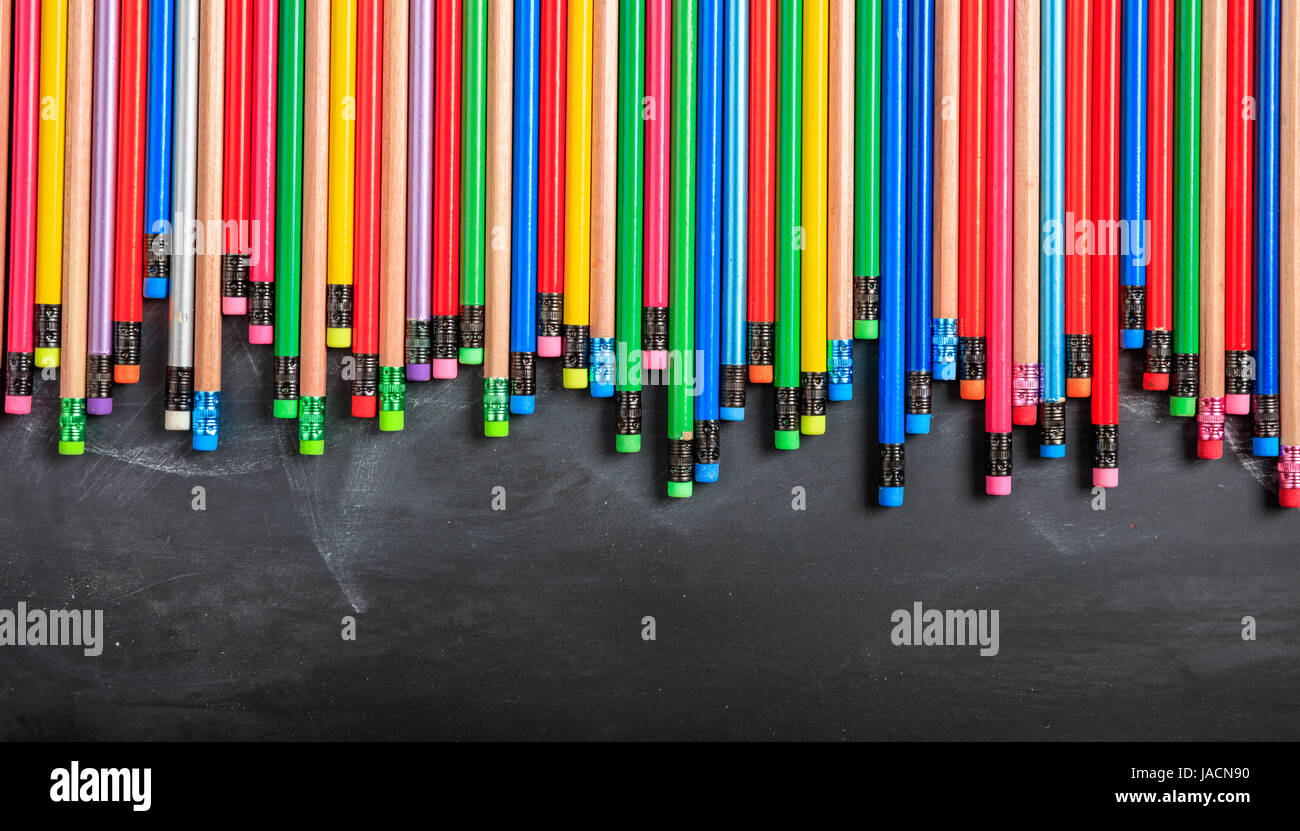 Bunte Bleistifte mit Radiergummi auf einer schwarzen Tafel Stockfoto