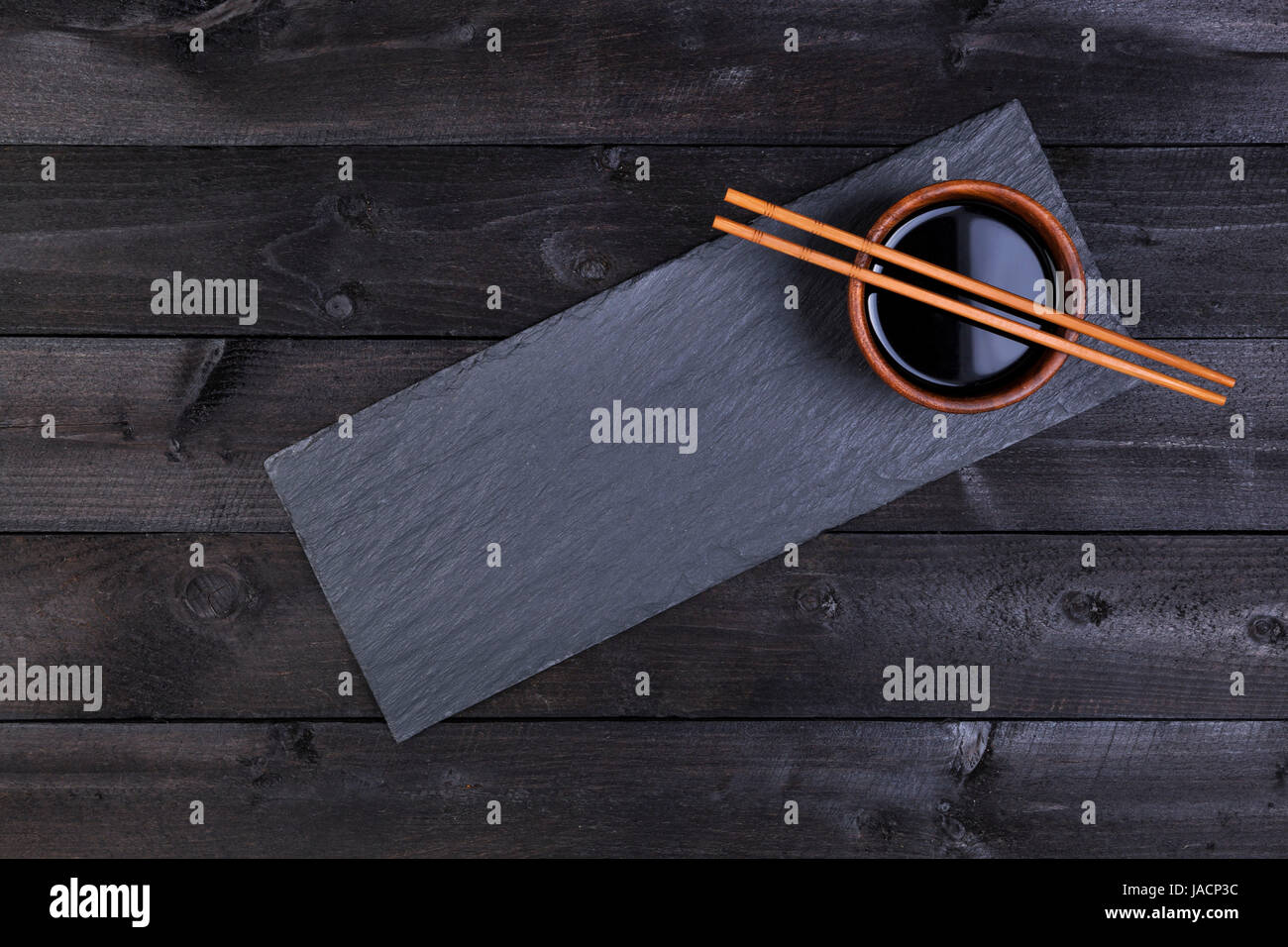 Zubehör für Sushi. Sojasauce, Stäbchen auf schwarzen Steinplatte. Draufsicht mit Textfreiraum Stockfoto