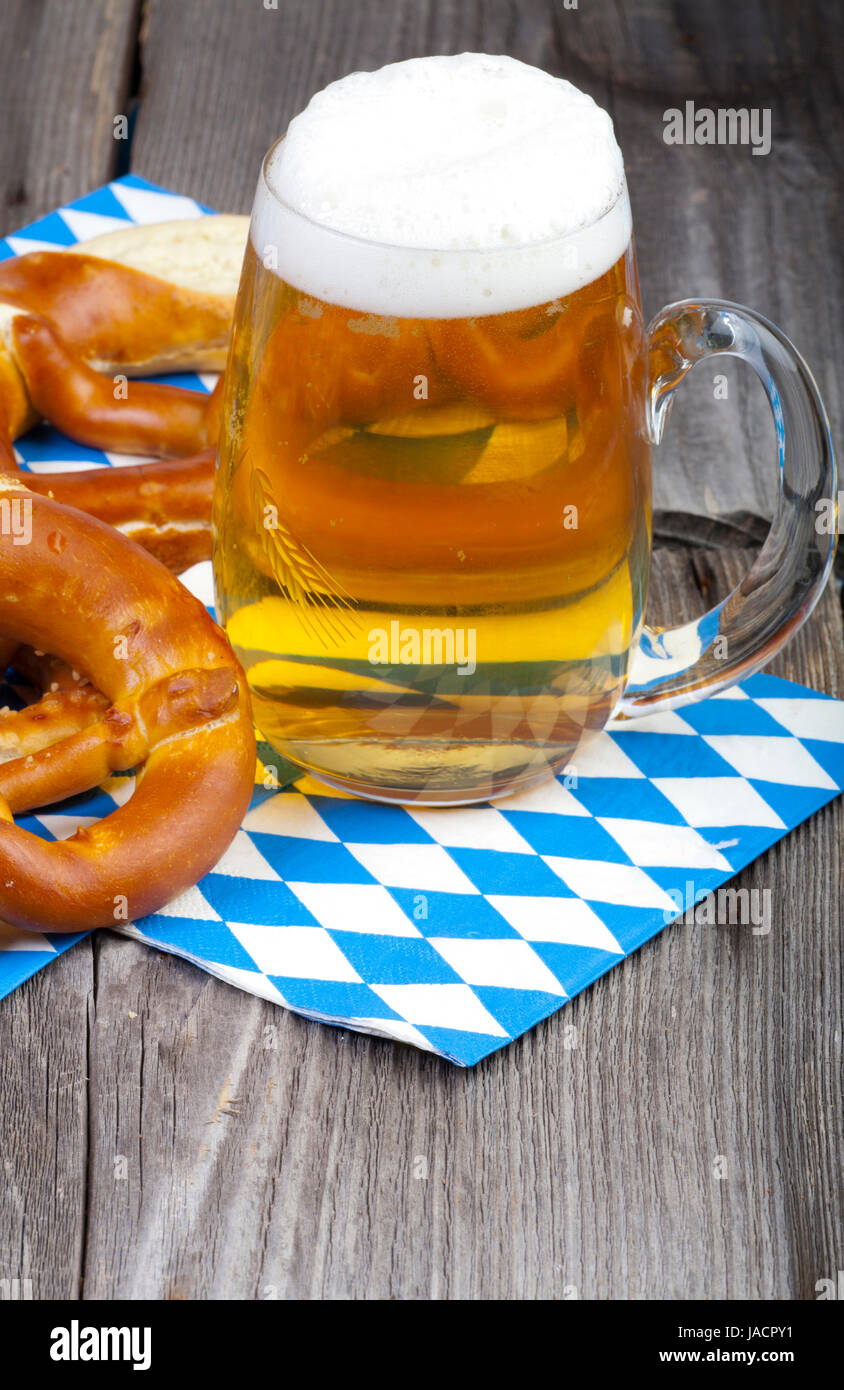 Ein Großes Kühles Bier Und Brezeln Auf Servietten Mit Blau-Weißen Rautenmuster Auf Einem alten Rustikalem Holztisch Stockfoto