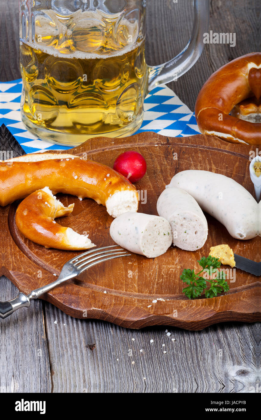 Rundes Holzbrett Mit Weißwurst, Brezel, Senf Und Radieschen Und Einem Glas Mit Bier Auf Einem alten Rustikalem Holztisch Stockfoto