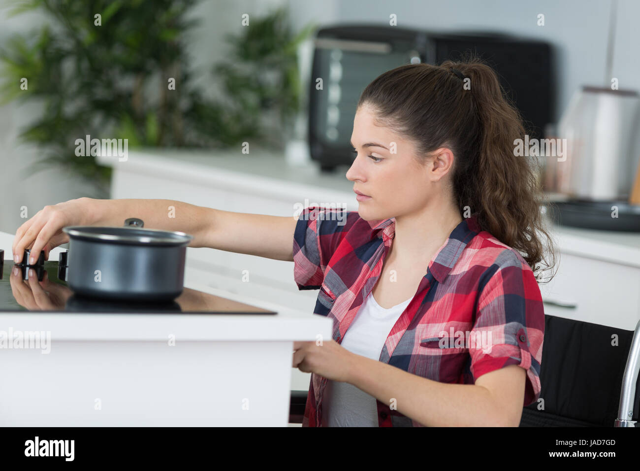 junge Frau im Rollstuhl kochen Abendessen deaktiviert Stockfoto