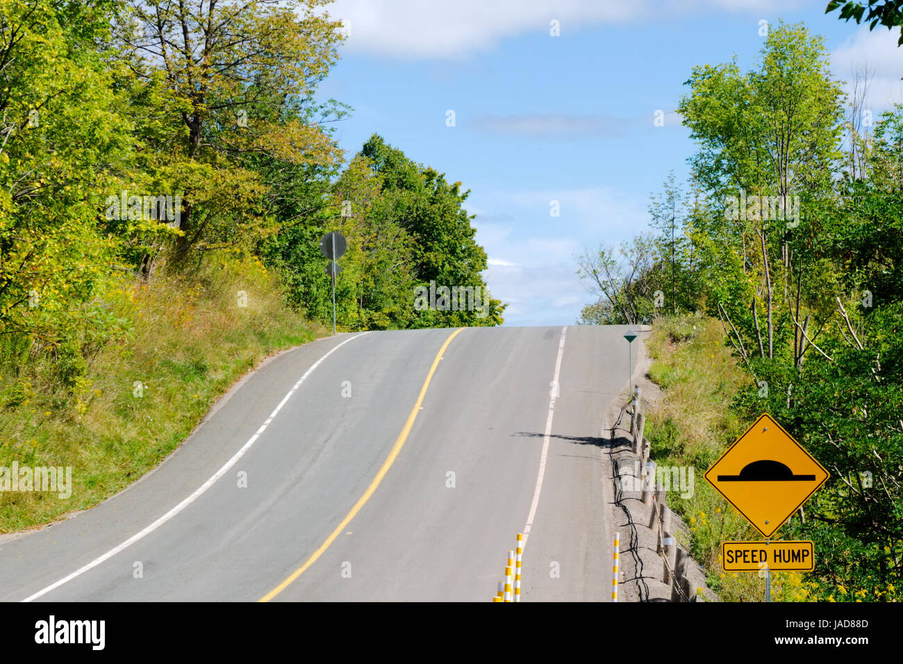 Hügel auf Landstraße mit gelben Bremsschwelle Warnschild. Stockfoto