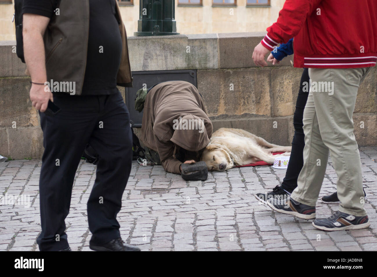 Menschen, die an einem Bettler und seinem Hund in Prag vorbeilaufen. Konzept: Obdachlose in Europa, Betteln, Armut, Bankrott, Menschen, die ignorieren Stockfoto