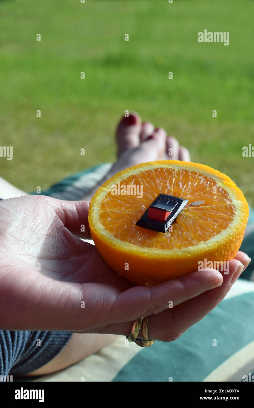 Einzigartige gesunde Ernährung Konzept. Die Hand der Frau eine Halteplatte mit saftige Orange mit eingefügten ein-/Ausschalter im Sinne einer Änderung zu gesünderen Leben. Stockfoto