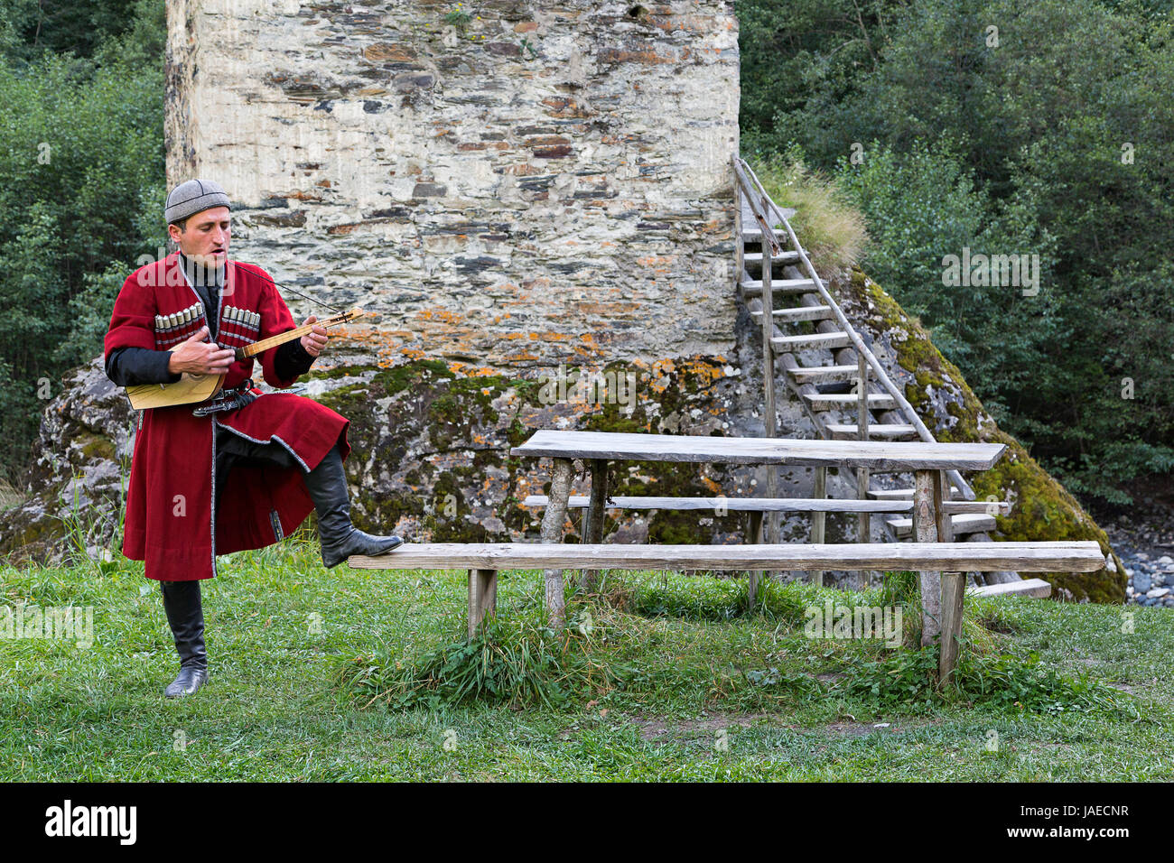 Georgischer Mann in nationalen Kostümen spielen lokale Musikinstrument als Panduri bekannt, im Dorf Ushguli, in Georgien. Stockfoto