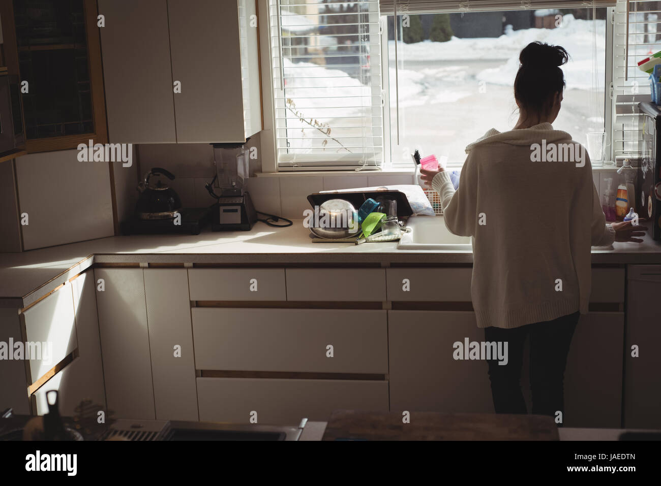 Rückansicht der Frau stand in der Nähe der Spüle zu Hause Stockfoto