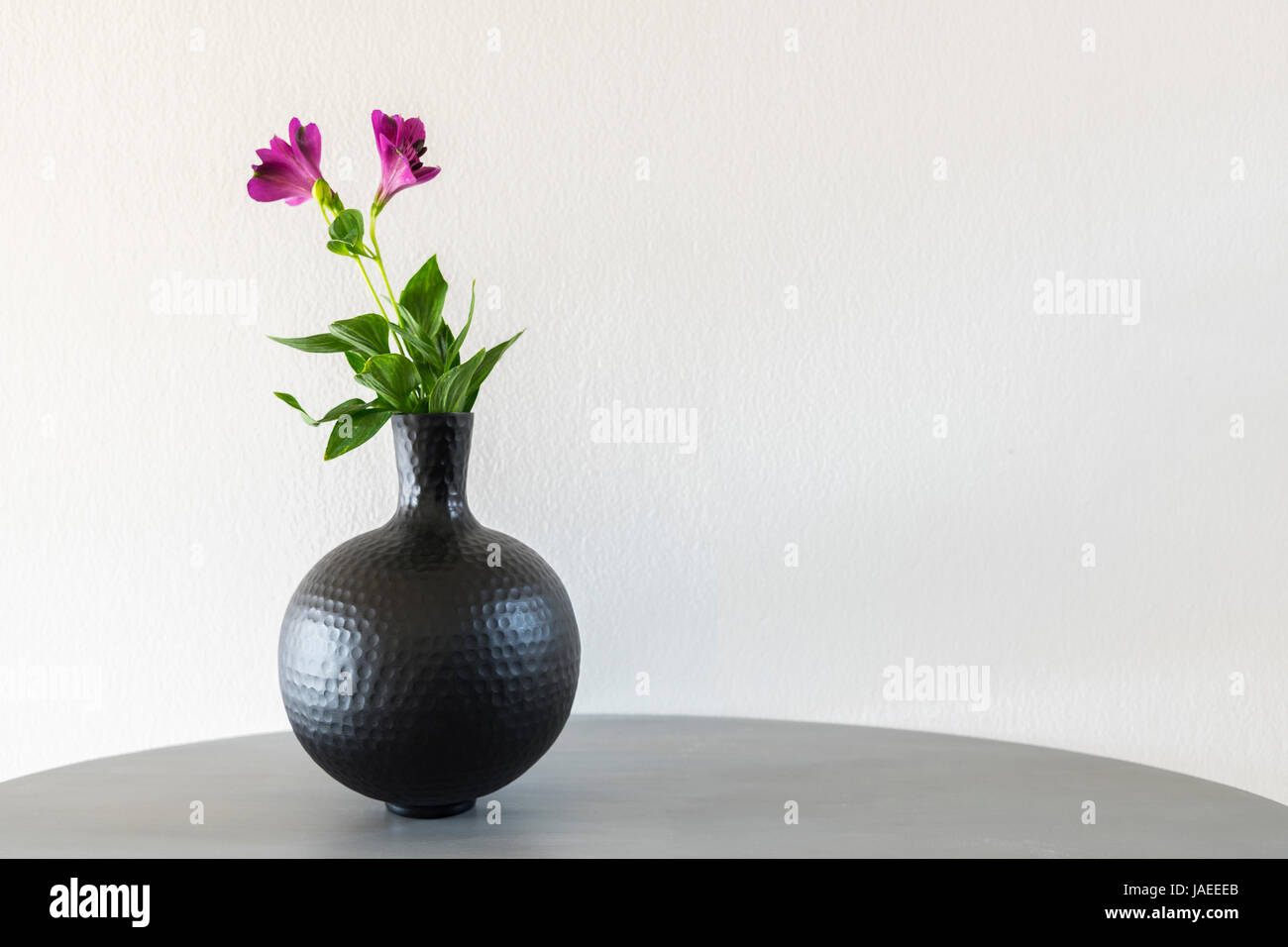 Zarte Blumen in Runde Metall Vase. Stockfoto