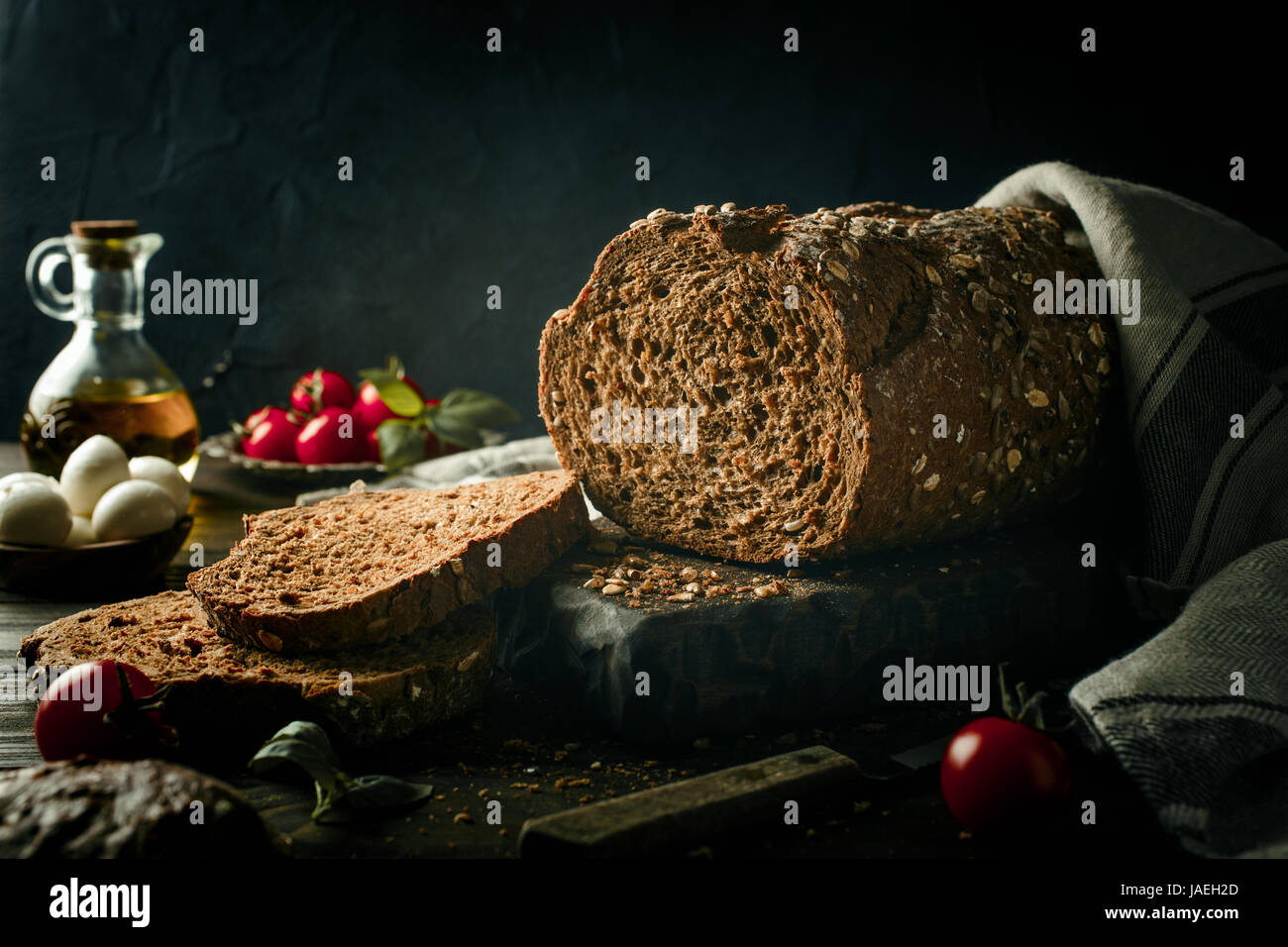 Vollkornbrot auf Holzbrett mit Olivenöl, Tomaten und Basilikum. Dunkel getönten Foto mit Textfreiraum. Stockfoto