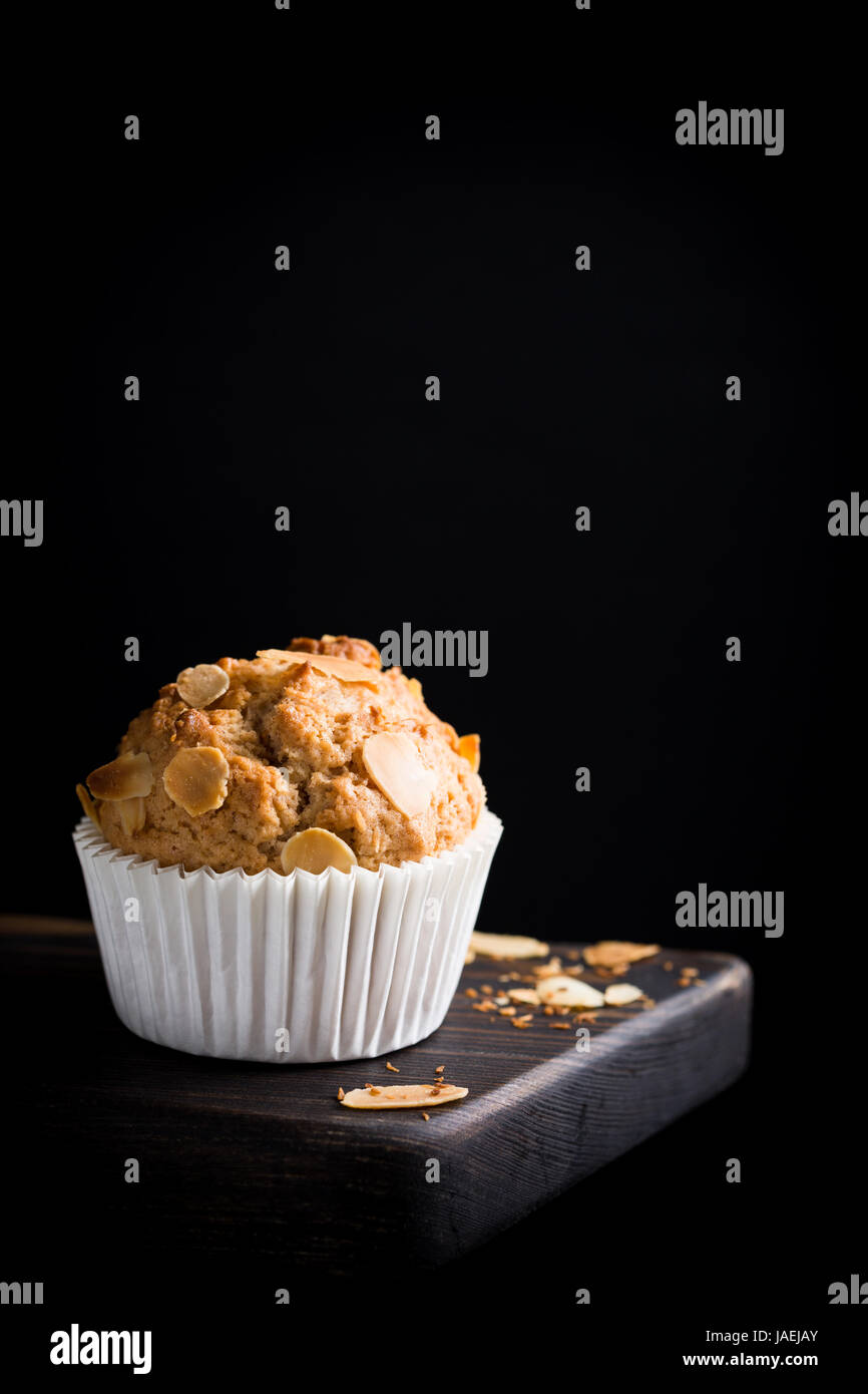 Köstliche hausgemachte Kokos Zimt Muffin mit Mandelblättchen auf schwarzem Hintergrund. Gesunde Ernährung-Konzept mit Textfreiraum. Stockfoto