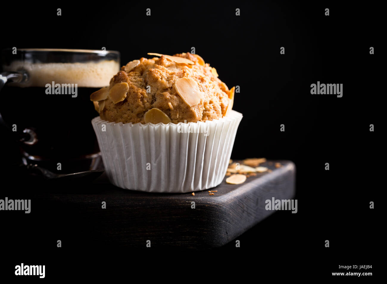 Köstliche hausgemachte Kokos Zimt Muffin mit Mandelblättchen auf schwarzem Hintergrund. Gesunde Ernährung-Konzept mit Textfreiraum. Stockfoto