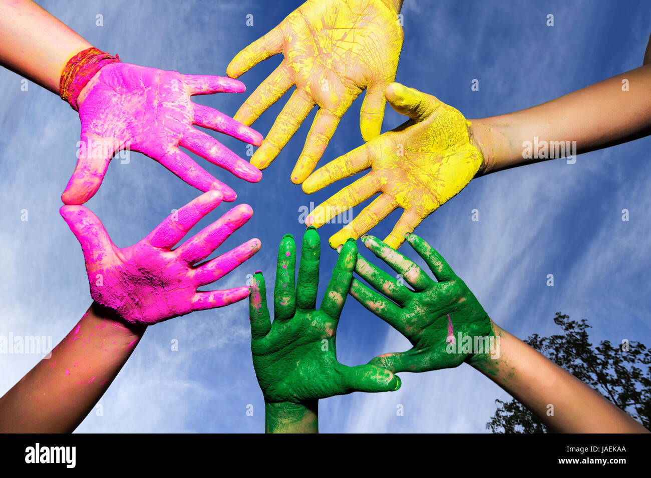 Hände / Palmen von Jugendlichen in rosa, gelb, grün Holi Festival Farben unter blauem Himmel bedeckt Stockfoto