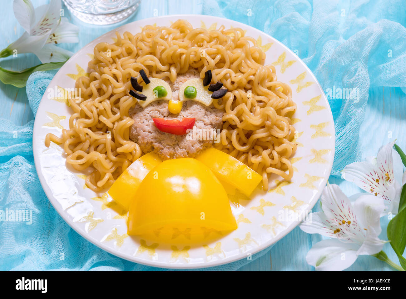 Lustiges Mädchen essen Gesicht mit Schnitzel, Pasta-Nudeln und Gemüse Stockfoto