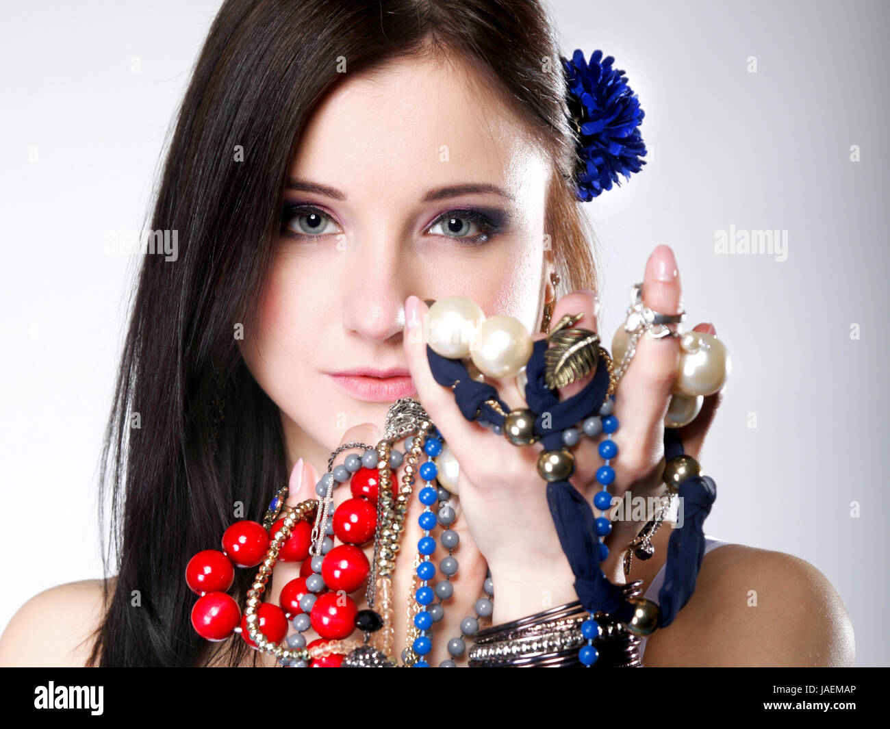 junge Frau im Sommerstil mit viel Schmuck, Perlen in Händen grauer  Hintergrund Stockfotografie - Alamy