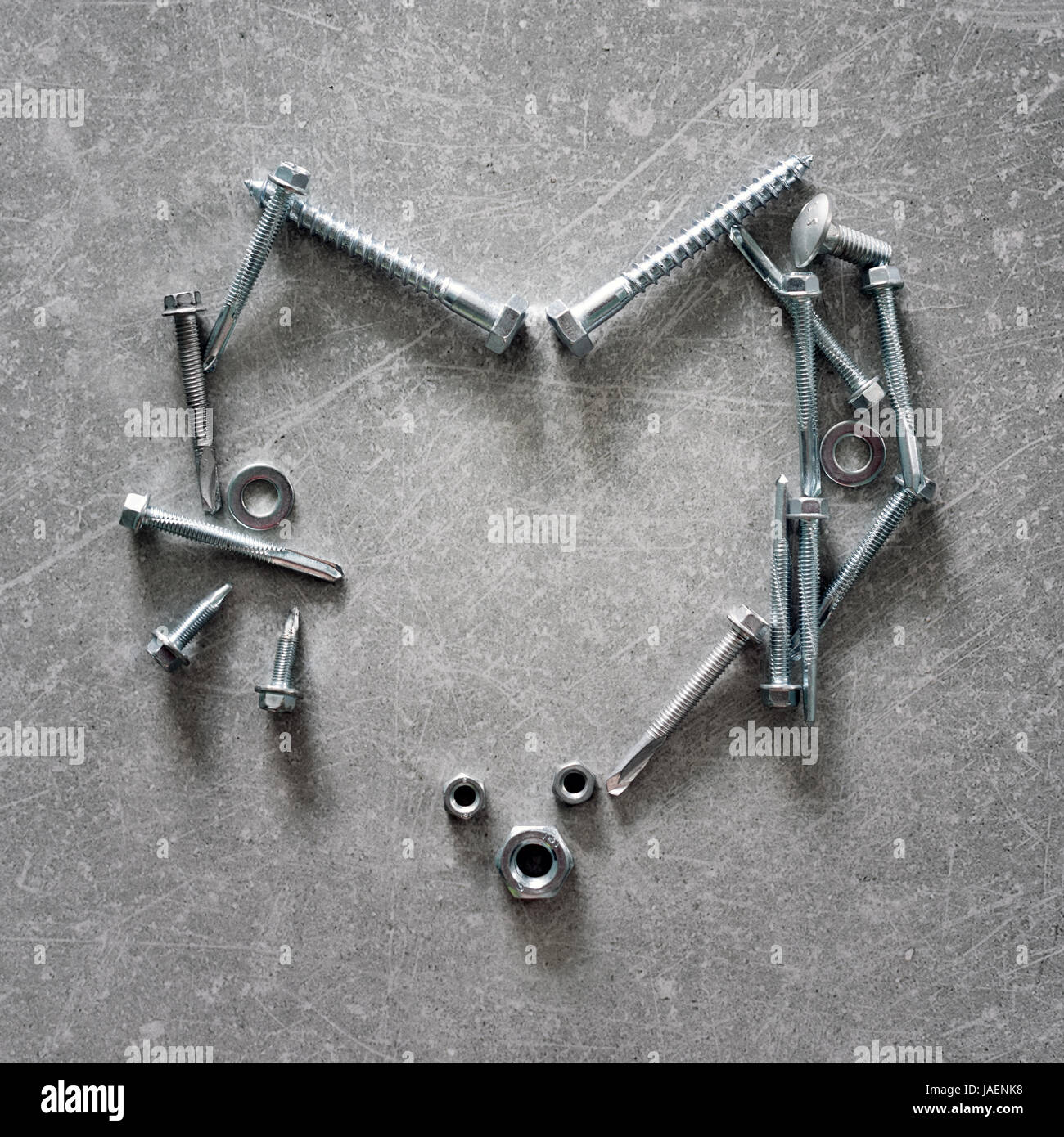 Herzsymbol gemacht von Schrauben, Muttern und Bolzen. Herzförmige Konstruktionswerkzeuge auf konkreten Hintergrund. Liebe Zeichen Stockfoto