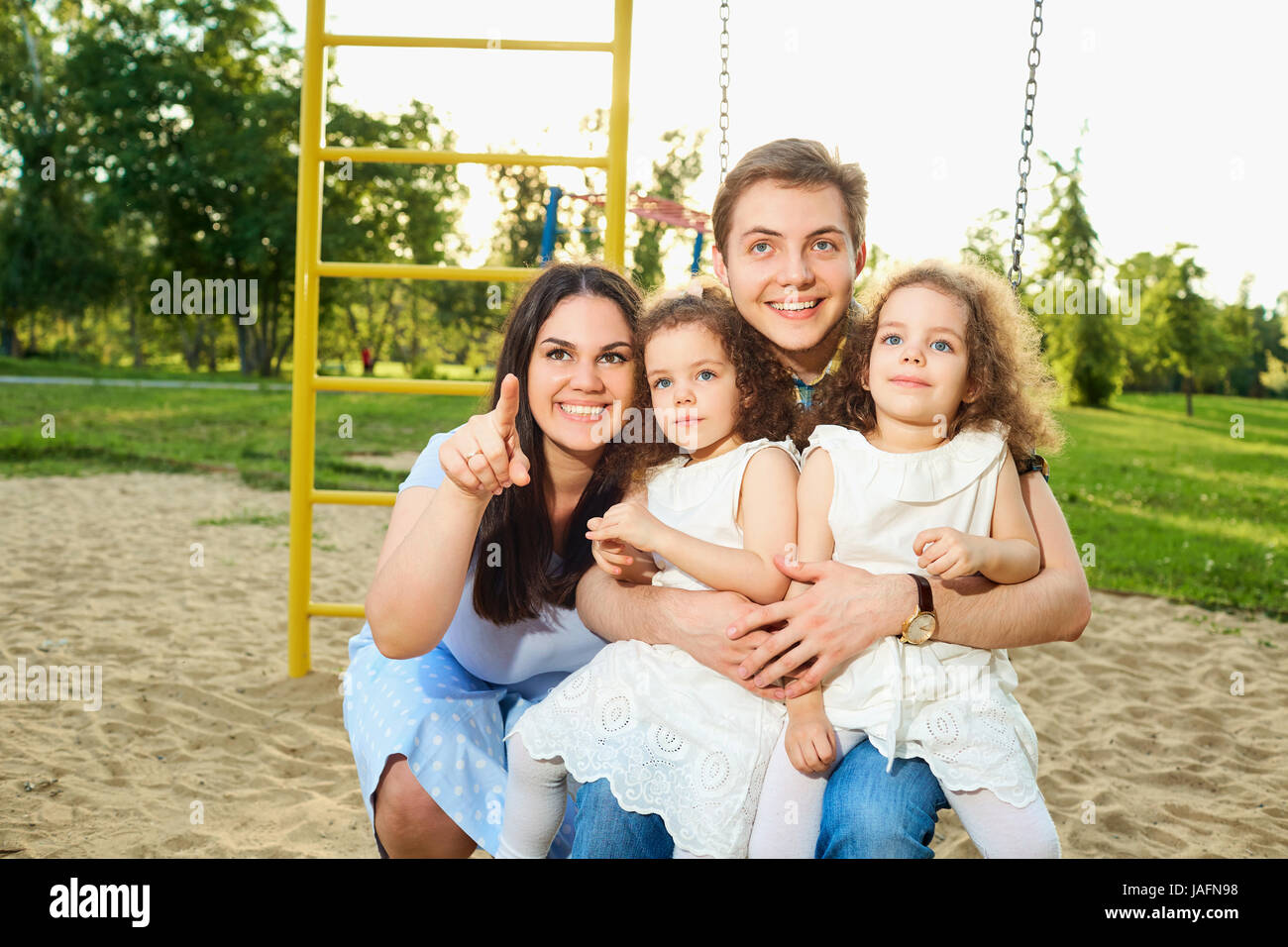 Glückliche Familie mit Kindern auf einer Schaukel auf dem Spielplatz Stockfoto