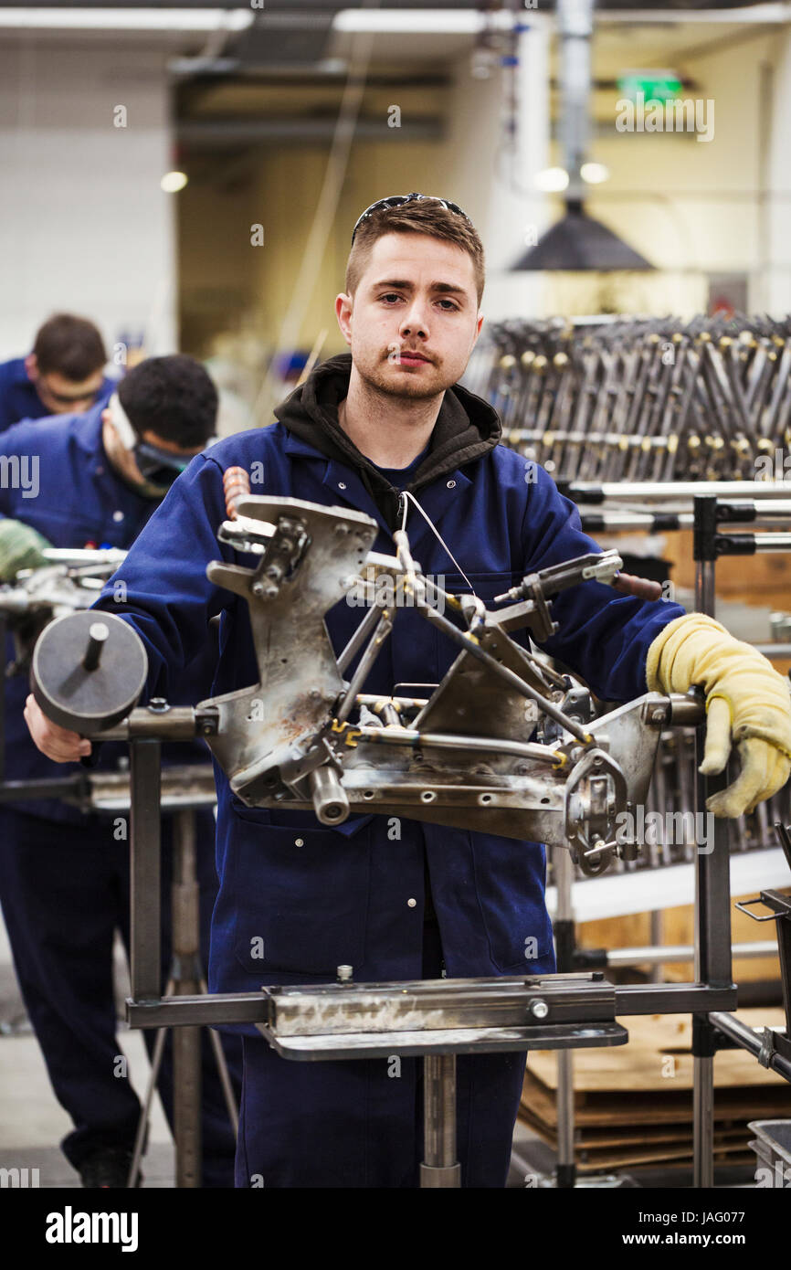 Männliche qualifizierte Fabrikarbeiter im Overall tragen ein Schutzhandschuh an einen Fahrradrahmen in einer Fabrik arbeiten. Stockfoto