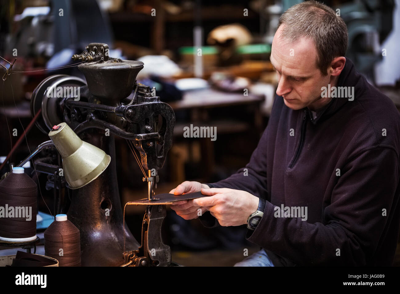 Mann sitzt auf einem großen Leder Naht Maschine in einer Schusterwerkstatt. Stockfoto