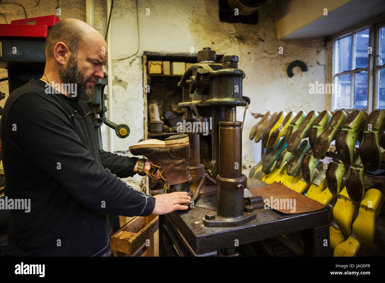 Mann stehend in einer Schusterwerkstatt, mit Hilfe einer Maschine, um ein Leder-Stiefelette zu machen. Stockfoto