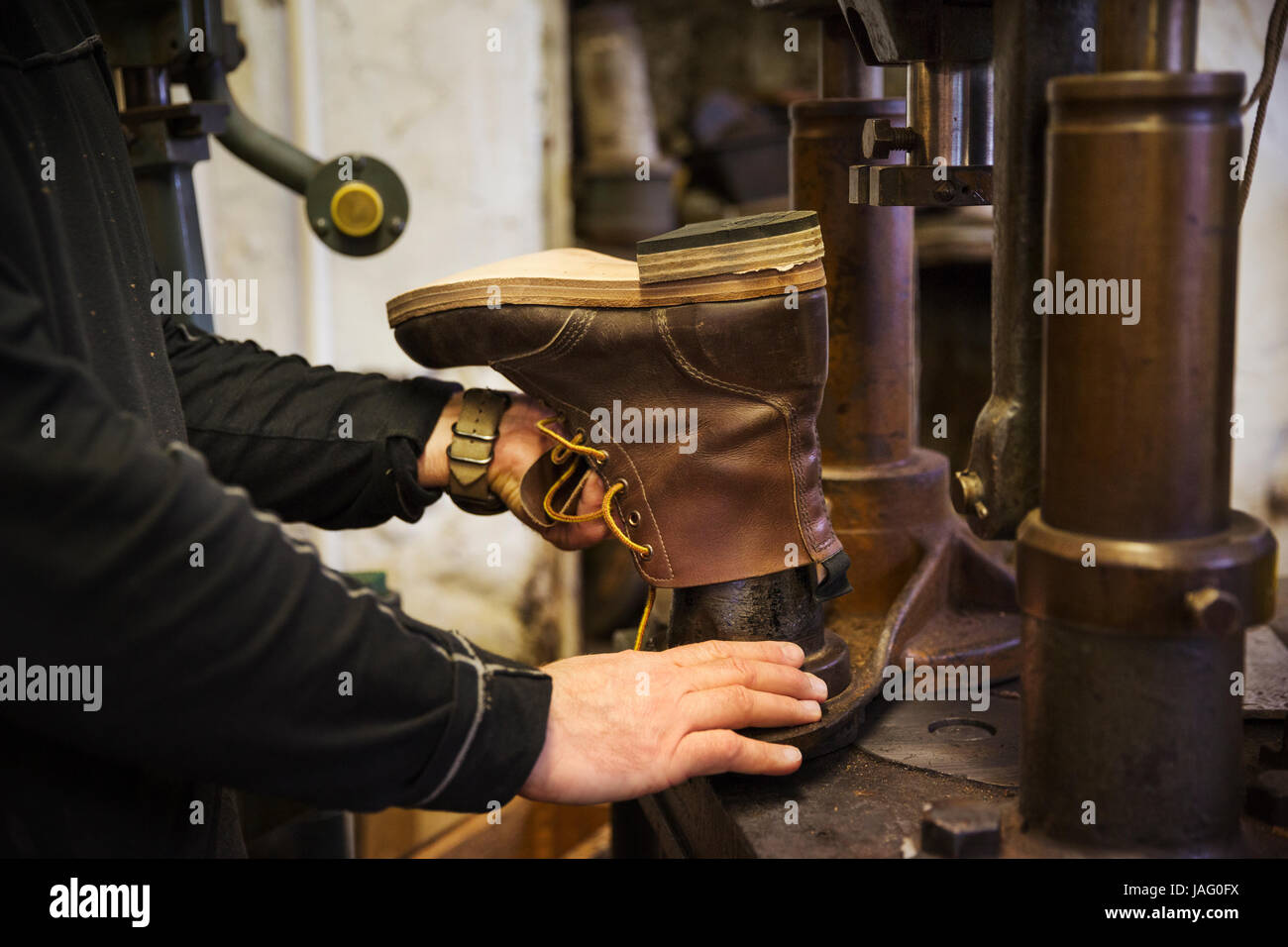 Nahaufnahme des Arbeitnehmers in eine Schusterwerkstatt mit Hilfe einer Maschine, um ein Leder-Stiefelette zu machen. Stockfoto