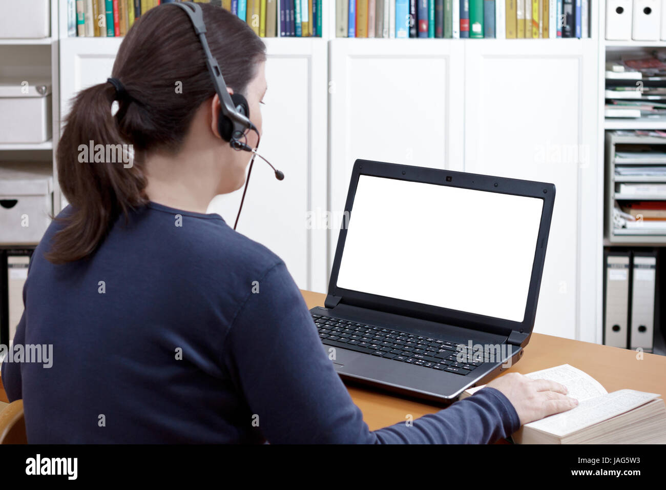 Frau mit Headset und buchen Sie an Ihrem Schreibtisch vor ihrem Laptop in eine Online Video Call, isolierte computer monitor, kopieren Raum Stockfoto
