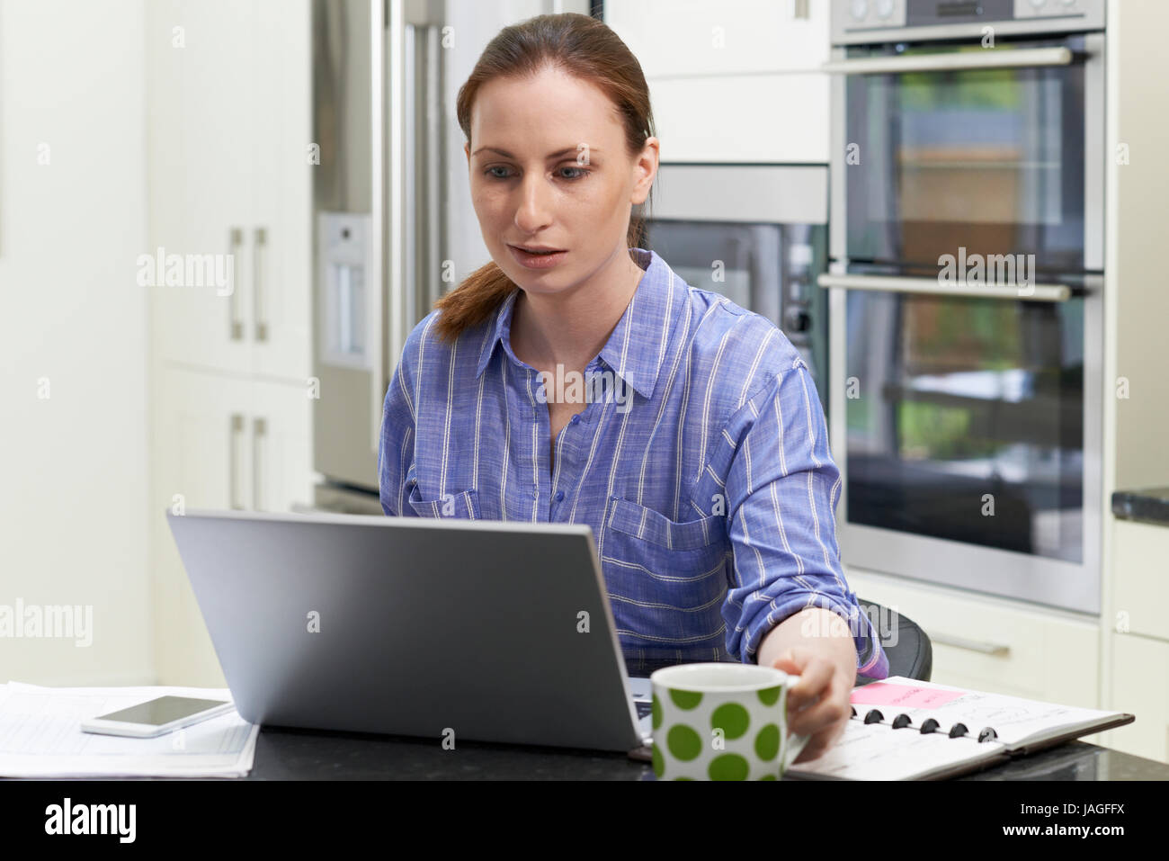 Freiberuflicher Arbeitnehmerin mit Laptop In der Küche zu Hause Stockfoto