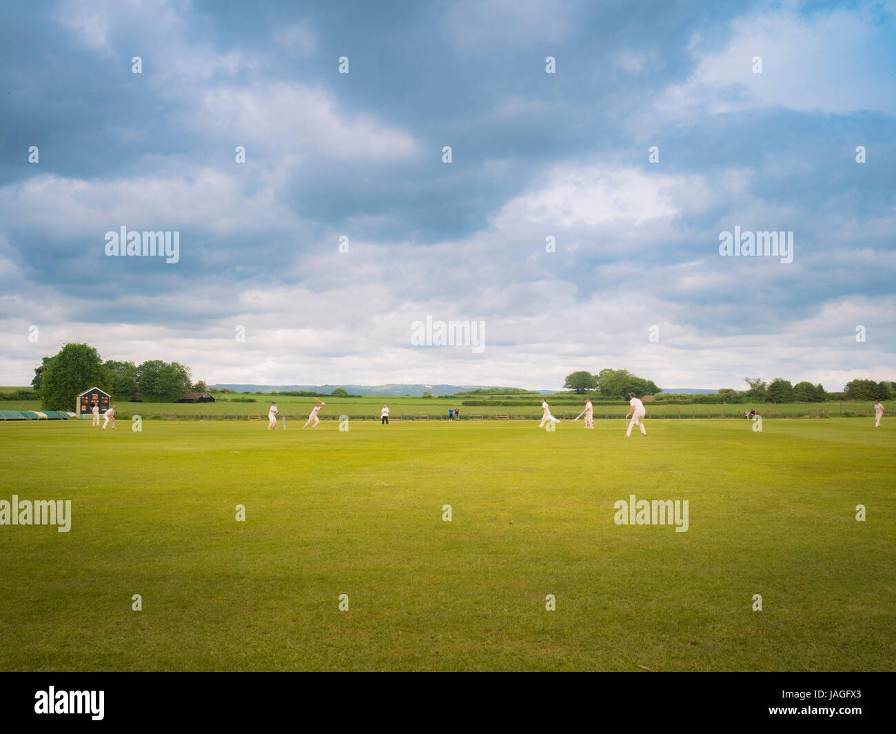 Spiel der Cricket in typisch britischen Dorf Sessay mit dem weißen Pferd im Hintergrund gespielt wird. Stockfoto