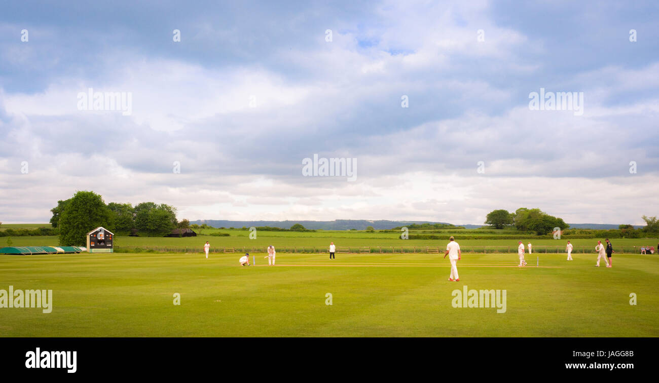 Spiel der Cricket in typisch britischen Dorf Sessay mit dem weißen Pferd im Hintergrund gespielt wird. Stockfoto