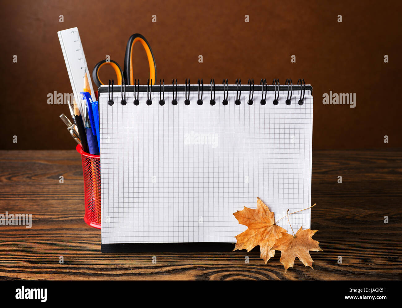 Ausstattung der Schule mit Bleistiften, Notebook und trockenen Herbst Blätter auf Holztisch. Zurück zur Schule oder zum Tag des Lehrers - Konzept. Stockfoto