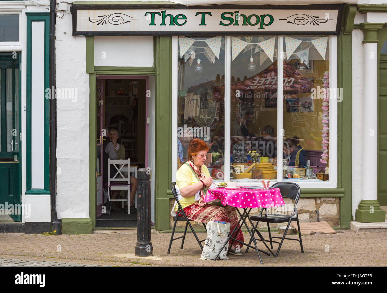 Frau, die im Juni vor dem T-Shop saß und etwas zu essen und zu trinken in Weymouth, Dorset UK, hatte Stockfoto